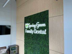 Interior lobby sign with illuminated lettering on green wall for Spring Green Family Dental